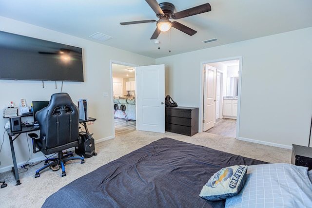 bedroom featuring baseboards, ensuite bathroom, visible vents, and light carpet