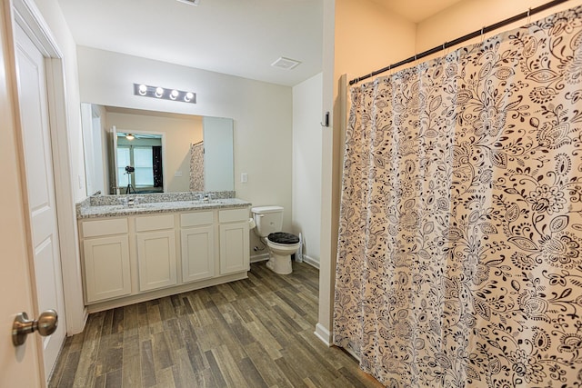 full bath with a shower with curtain, vanity, toilet, visible vents, and wood finished floors