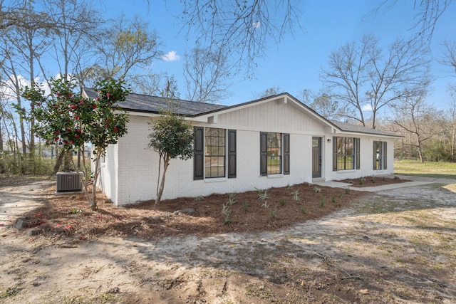 view of side of home featuring brick siding and central AC unit