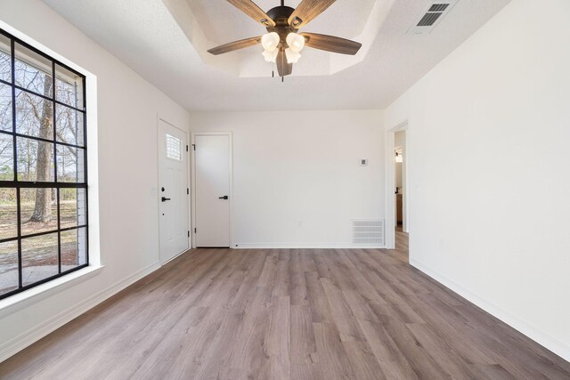 empty room with a wealth of natural light, a raised ceiling, and visible vents