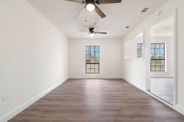 spare room with baseboards, a textured ceiling, visible vents, and wood finished floors