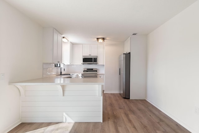 kitchen with visible vents, appliances with stainless steel finishes, a peninsula, light countertops, and a sink