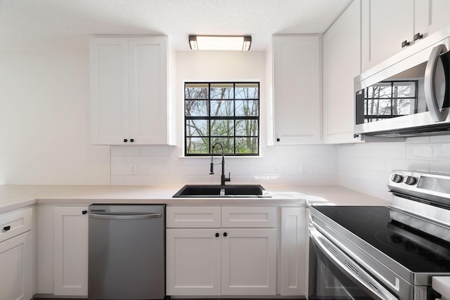 kitchen with white cabinetry, decorative backsplash, stainless steel appliances, and a sink