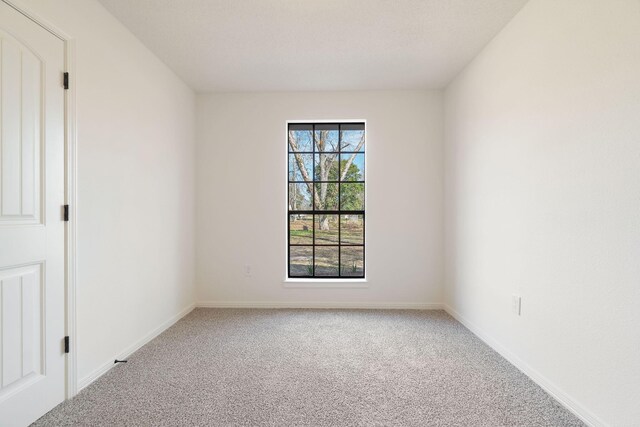 carpeted empty room featuring baseboards