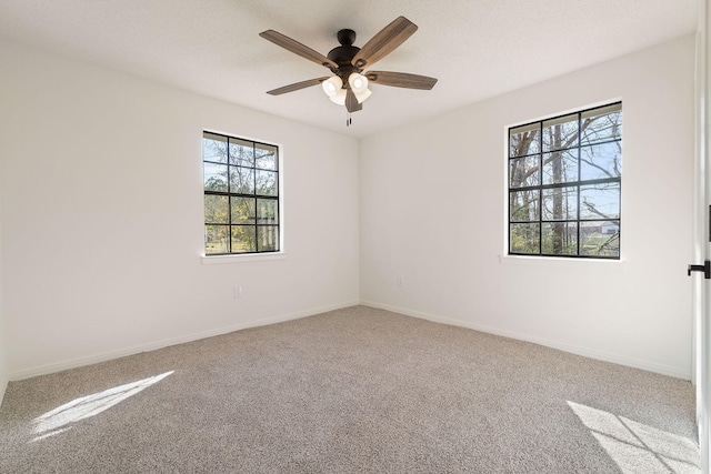 carpeted spare room featuring ceiling fan and baseboards