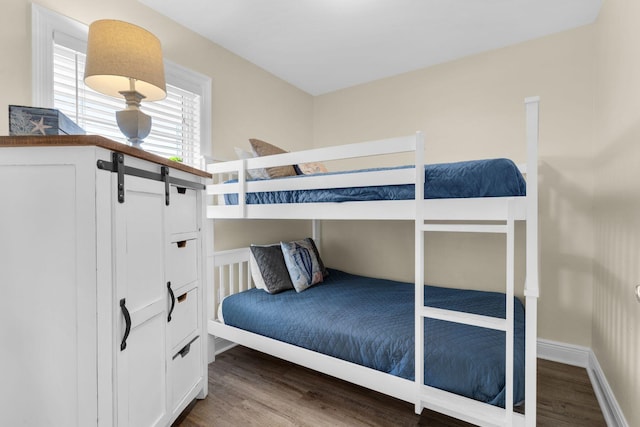 bedroom featuring a barn door, baseboards, and wood finished floors