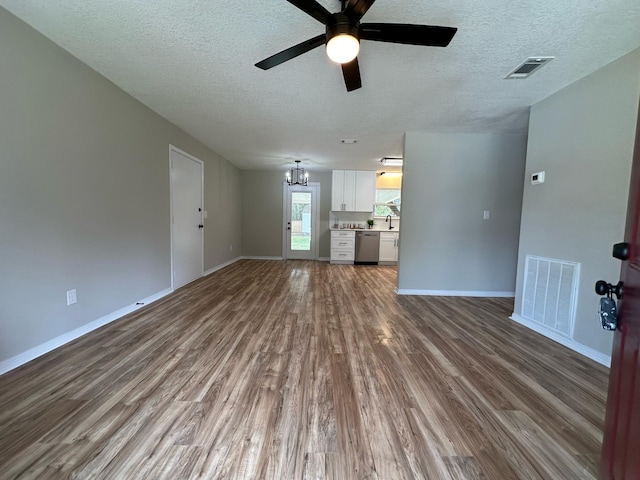 unfurnished living room featuring visible vents, baseboards, and wood finished floors