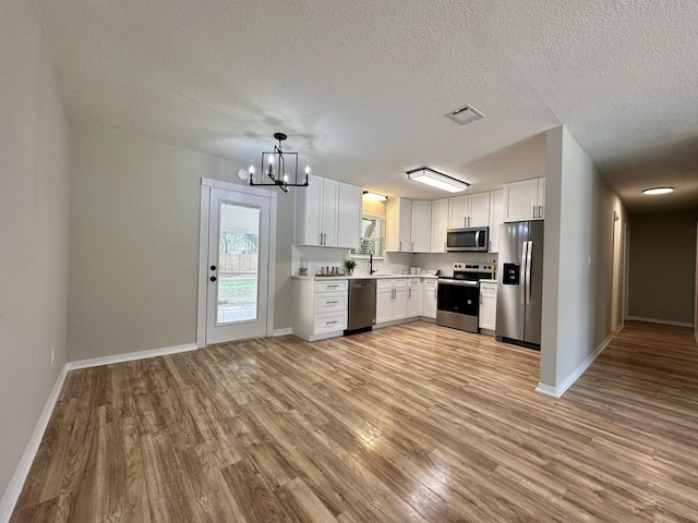 kitchen featuring visible vents, light countertops, light wood-style flooring, appliances with stainless steel finishes, and white cabinetry