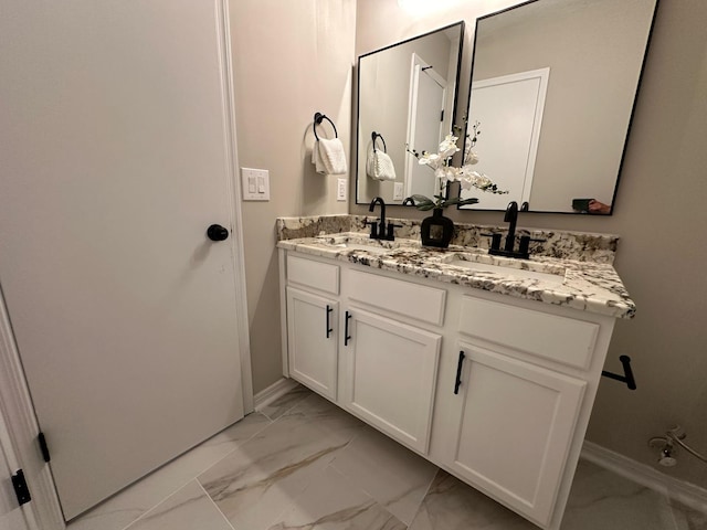 full bath with double vanity, baseboards, marble finish floor, and a sink