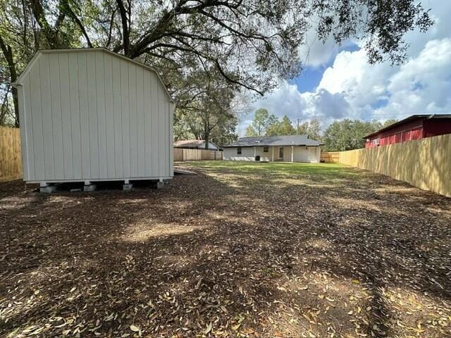 view of yard with a storage unit, an outbuilding, and fence