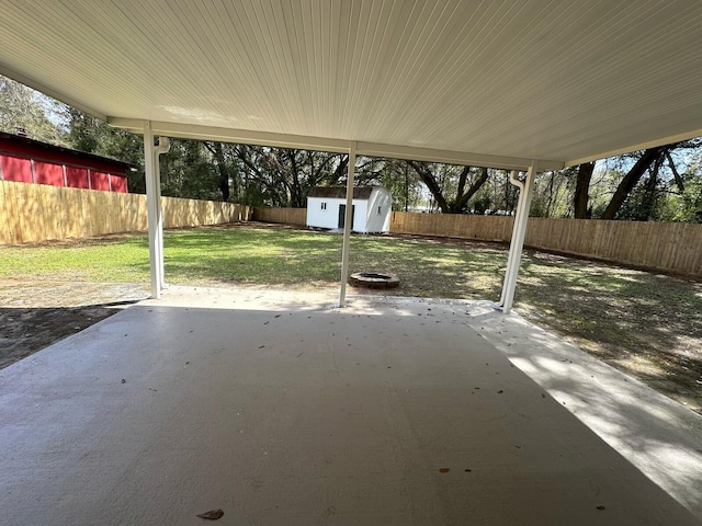 view of patio / terrace featuring an outbuilding, a storage unit, and a fenced backyard