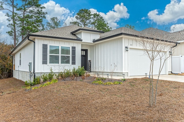 view of front facade featuring a garage, driveway, a shingled roof, fence, and board and batten siding