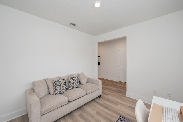 living area with light wood finished floors, visible vents, and baseboards