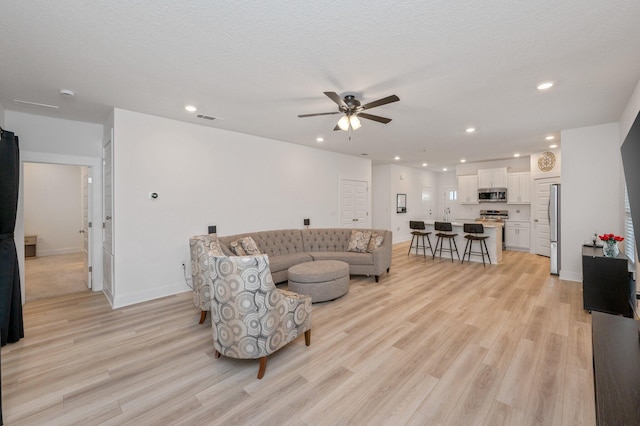 living area featuring light wood-type flooring, visible vents, baseboards, and recessed lighting