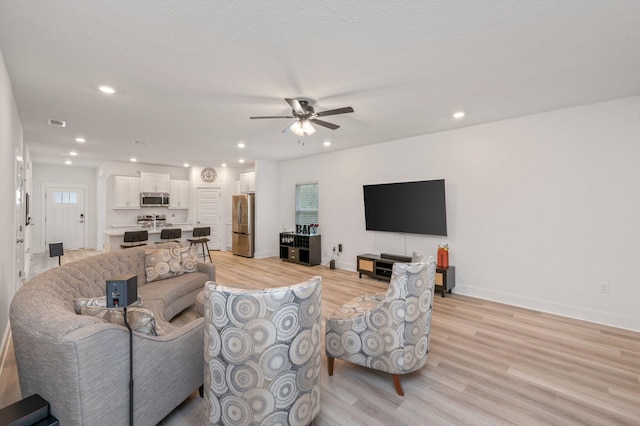 living area with ceiling fan, recessed lighting, visible vents, baseboards, and light wood-style floors