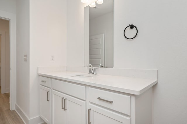 bathroom with wood finished floors, vanity, and baseboards