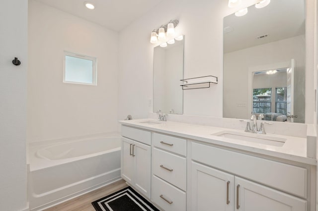 bathroom with ensuite bathroom, double vanity, a sink, and visible vents