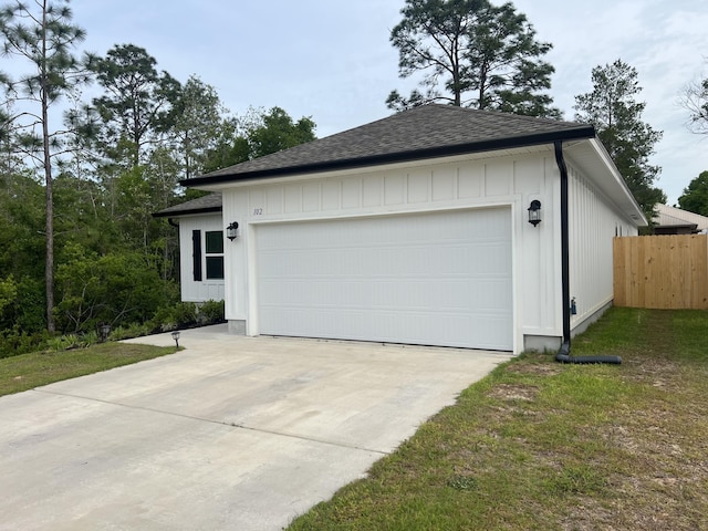 garage featuring concrete driveway and fence