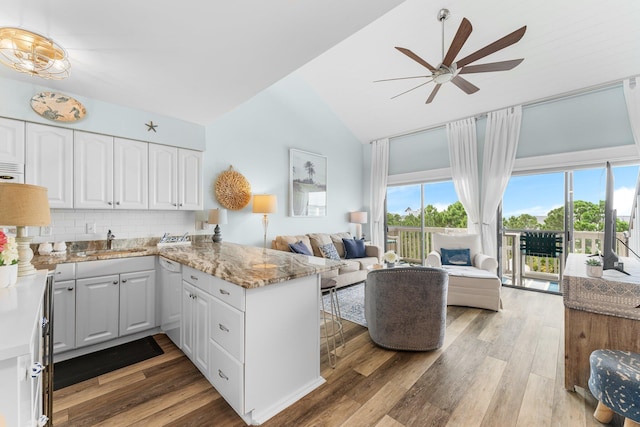 kitchen featuring open floor plan, a peninsula, light wood-type flooring, white cabinetry, and a sink