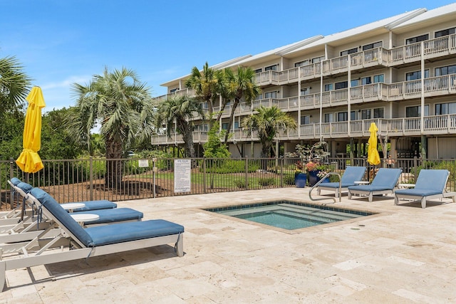 view of pool with a patio, fence, and a hot tub