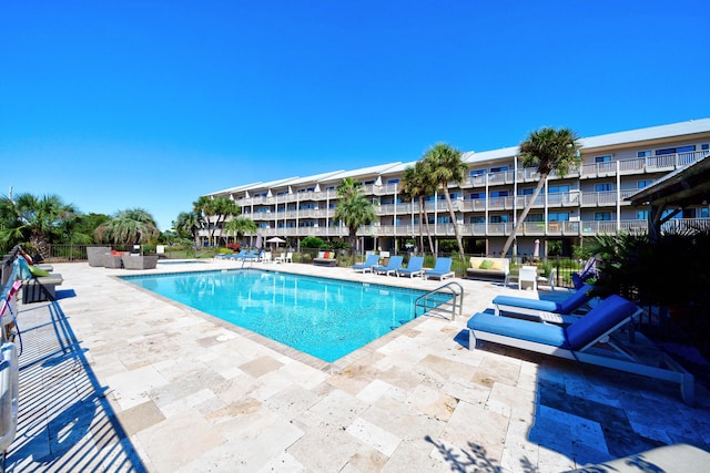 community pool with a patio area and fence