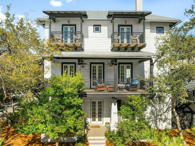 view of front facade with french doors, a balcony, metal roof, and a standing seam roof