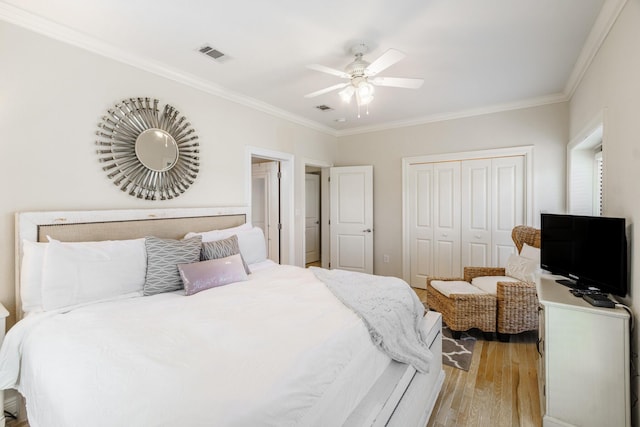 bedroom featuring crown molding, light wood-style flooring, visible vents, and a closet