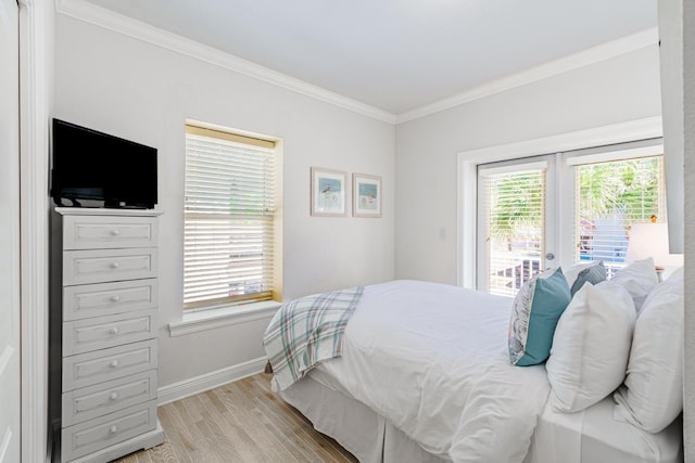 bedroom featuring access to exterior, light wood finished floors, crown molding, and baseboards