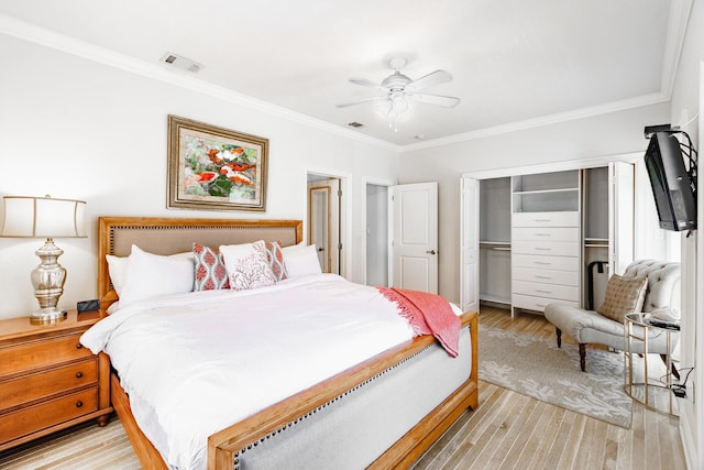 bedroom with crown molding, light wood-style floors, visible vents, and a closet