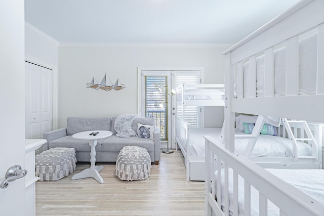 bedroom with a closet, wood finished floors, crown molding, and access to outside