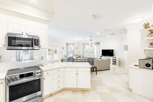 kitchen with a healthy amount of sunlight, appliances with stainless steel finishes, white cabinetry, and ornamental molding