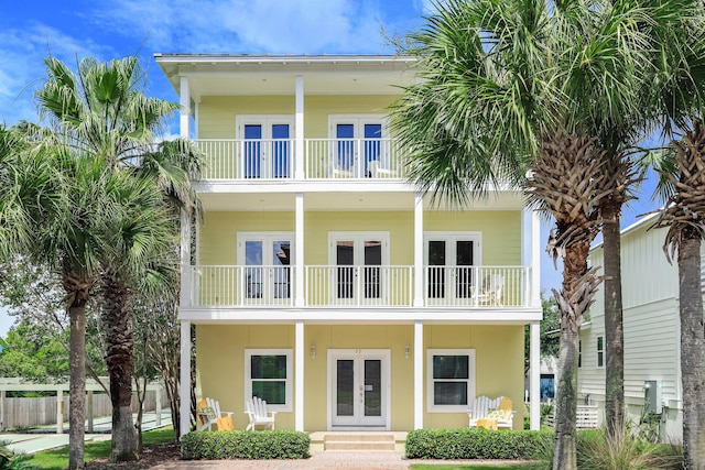 exterior space featuring a balcony, covered porch, fence, and french doors