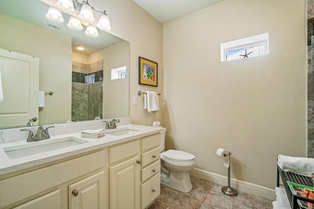 full bathroom with baseboards, visible vents, a tile shower, and a sink