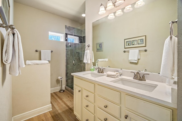 bathroom with a shower stall, wood finished floors, double vanity, and a sink