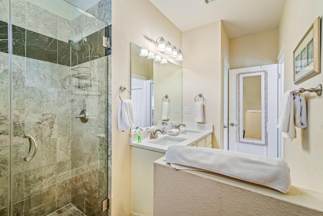 bathroom with double vanity, a shower stall, and a sink