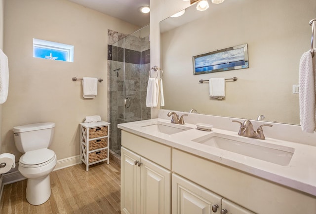 bathroom featuring a tile shower, wood finished floors, toilet, and a sink