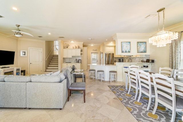 living area with stairway, recessed lighting, ceiling fan with notable chandelier, and ornamental molding