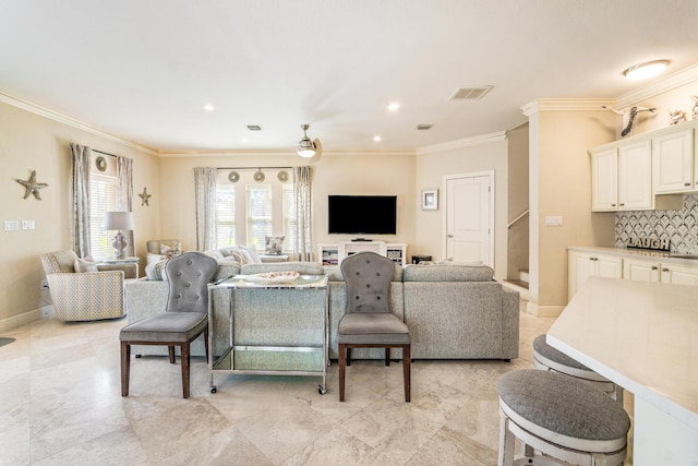 living area featuring visible vents, baseboards, and crown molding