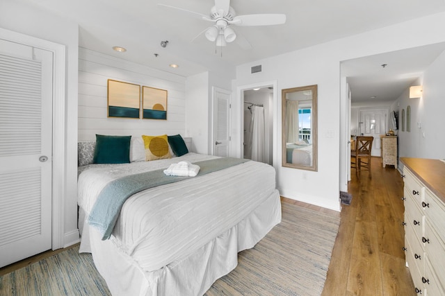 bedroom featuring light wood finished floors, wooden walls, baseboards, visible vents, and ceiling fan