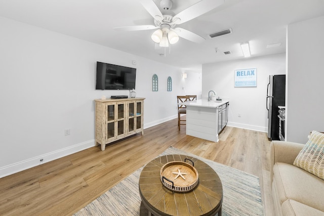 living area with light wood-type flooring, baseboards, visible vents, and a ceiling fan