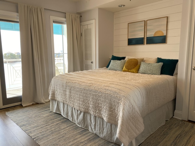 bedroom featuring wood walls, multiple windows, and wood finished floors