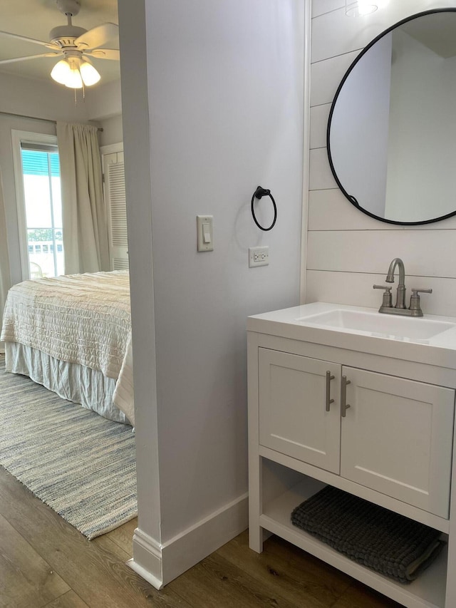 ensuite bathroom with a ceiling fan, vanity, ensuite bath, wood finished floors, and baseboards