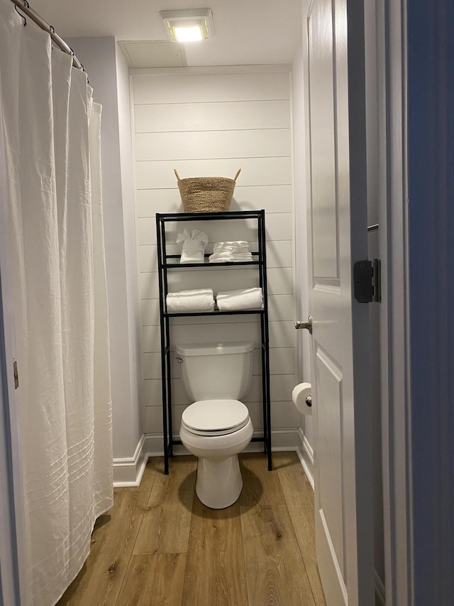 bathroom with toilet, baseboards, and wood finished floors