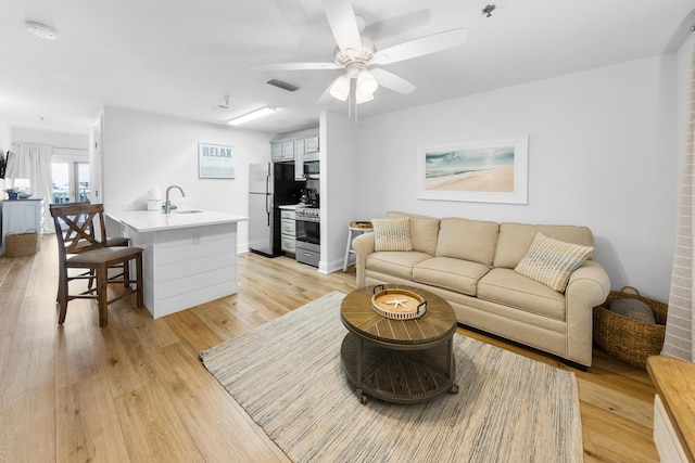 living area featuring ceiling fan, baseboards, visible vents, and light wood-style floors