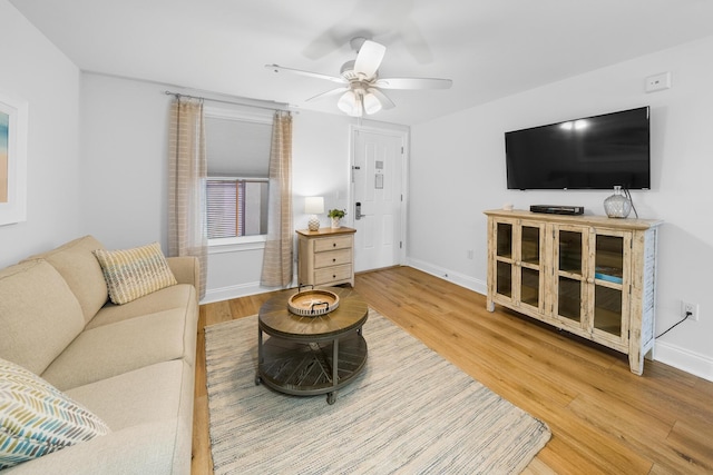 living area featuring ceiling fan, baseboards, and wood finished floors