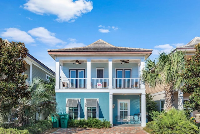 view of front of house with a balcony, a ceiling fan, and stucco siding