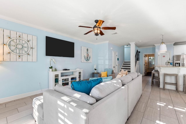 living area featuring baseboards, visible vents, a ceiling fan, stairway, and crown molding