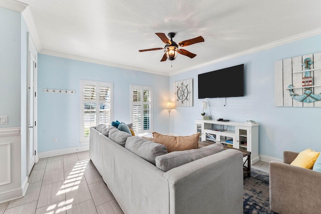 living area with a textured ceiling, ornamental molding, a ceiling fan, and baseboards