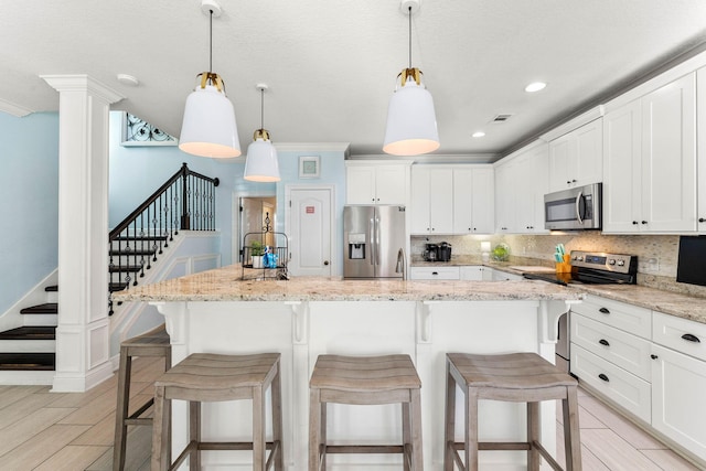 kitchen with ornamental molding, appliances with stainless steel finishes, backsplash, and white cabinets