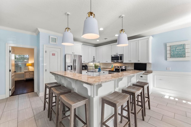 kitchen with crown molding, stainless steel appliances, light stone counters, and white cabinets